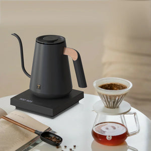 Bouilloire électrique noire avec détail en bois sur la poignée et bec étroit pour barista et accessoires café filtre, tout sur le café.