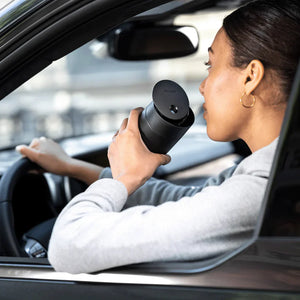 Personne boit du café dans un mug isotherme noir avec couvercle coulissant dans une voiture, partie de Take away, Fellow, EspressoGear, tout sur le café.