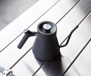 Bouilloire noire mate avec col de cygne étroit et thermomètre intégré, accessoires de préparation, tout sur le café.