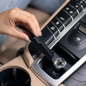 Main connectant le chargeur de voiture Ember à la prise allume-cigare pour une charge facile.